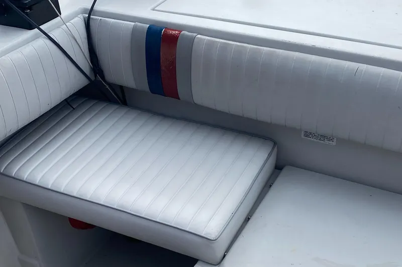 Slide: The Image of 1991 Penn Yan 215 Tempest boat interior with white cushioned seating and striped accents. - 9