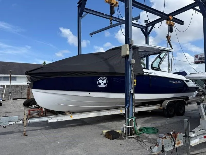 Slide: The Image of 2025 Monterey Elite 30 OB boat on trailer, covered, in a marina setting. - 14