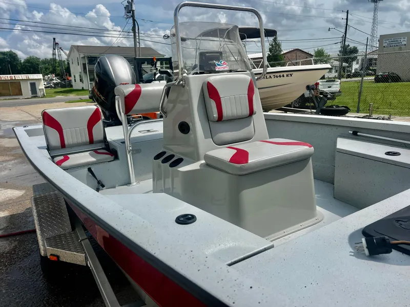 Slide: The Image of 2018 G3 Bay 18 DLX boat with red and white seating, parked outdoors. - 6
