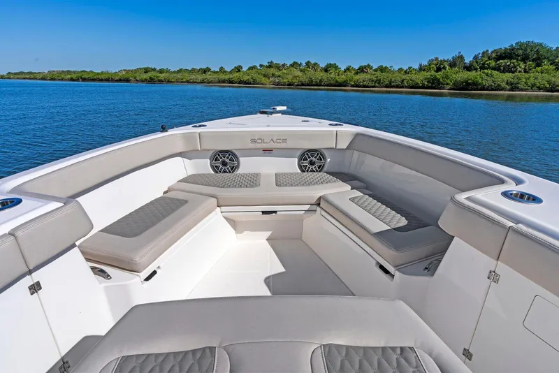 Slide: The Image of 2025 Solace 32 CS boat interior with cushioned seating, on a calm waterway. - 4