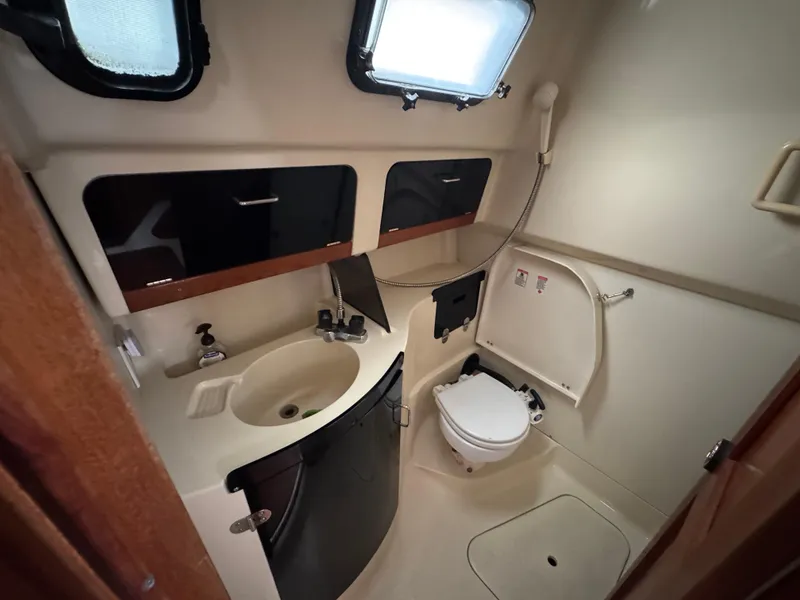 Slide: The Image of Compact bathroom in a 1994 Hunter 29.5 sailboat, featuring sink, toilet, and storage cabinets. - 11