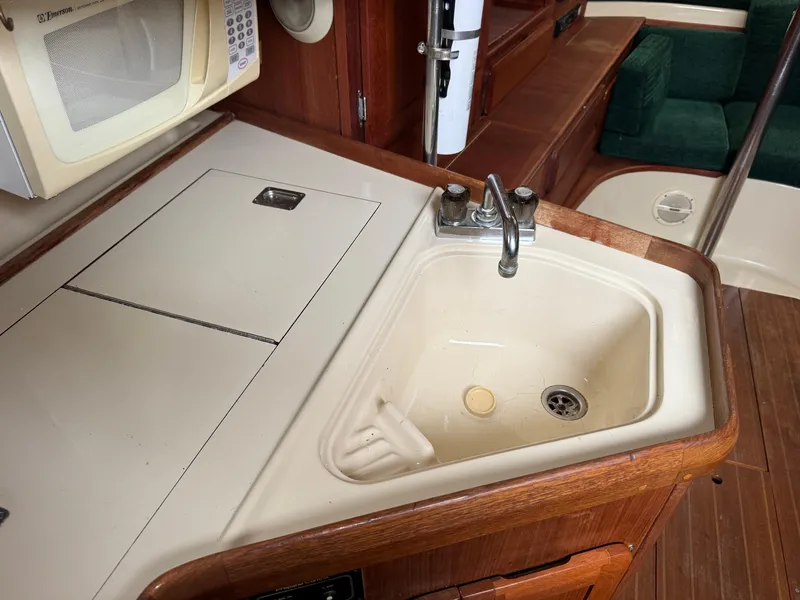 Slide: The Image of 1994 Hunter 29.5 yacht kitchen with sink, microwave, and wooden cabinetry. - 14