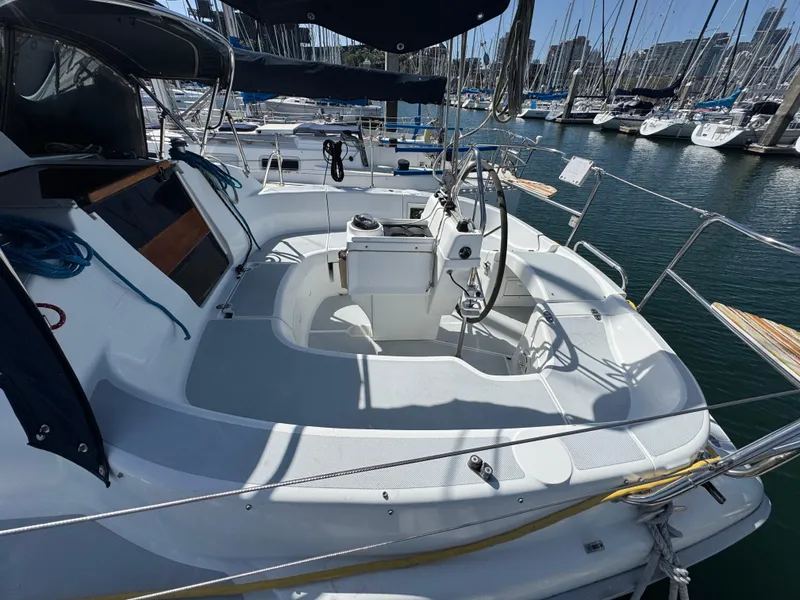 Slide: The Image of 1994 Hunter 29.5 sailboat cockpit with steering wheel, docked in marina. - 2