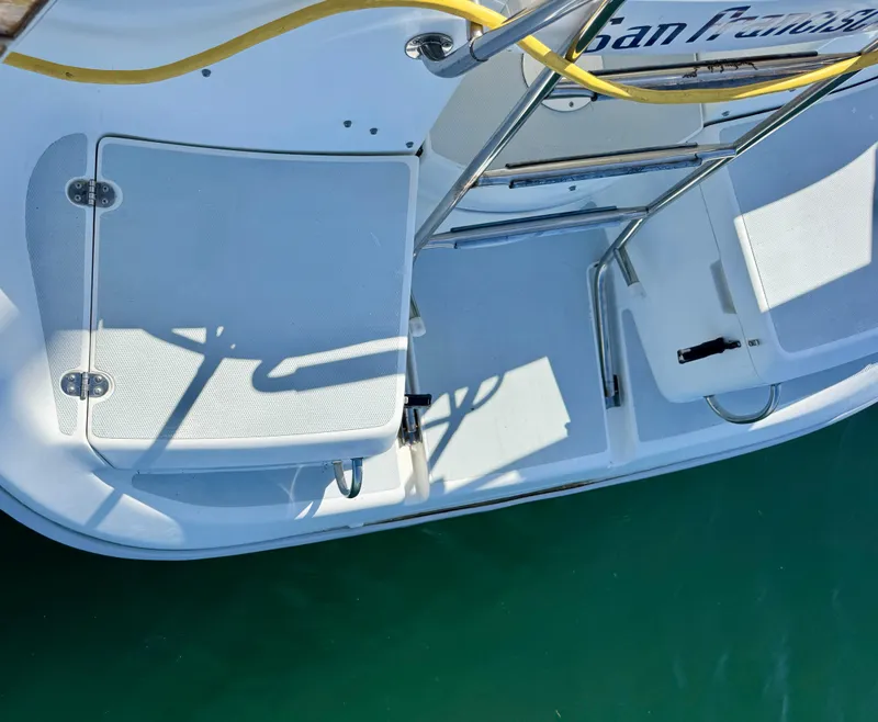 Slide: The Image of 1994 Hunter 29.5 boat stern with swim platform and ladder, docked on clear water. - 3