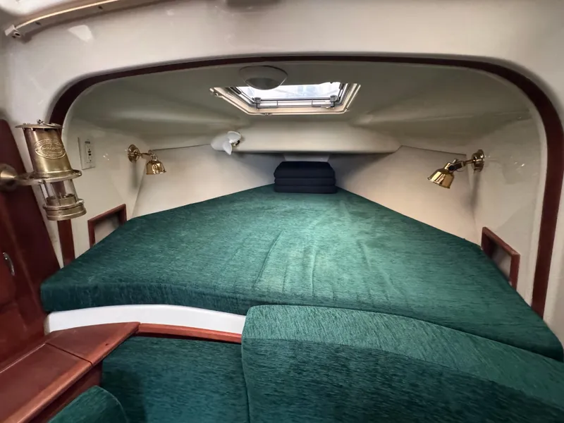 Slide: The Image of 1994 Hunter 29.5 sailboat cabin with green bedding and brass lamps. - 9