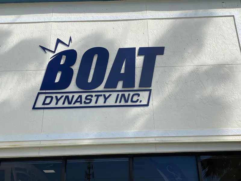 Slide: The Image of Boat Dynasty Inc. sign on building wall, featuring Contender 23 Open, 2002 model. - 23