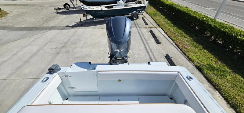 Slide: The Image of 2002 Contender 23 Open boat with outboard motor, parked on concrete near greenery. - 5