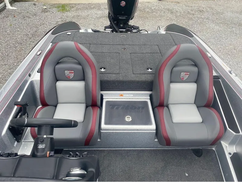 Slide: The Image of 2024 Triton 179 TrX boat interior with dual gray and red seats, steering wheel, and carpeted deck. - 10