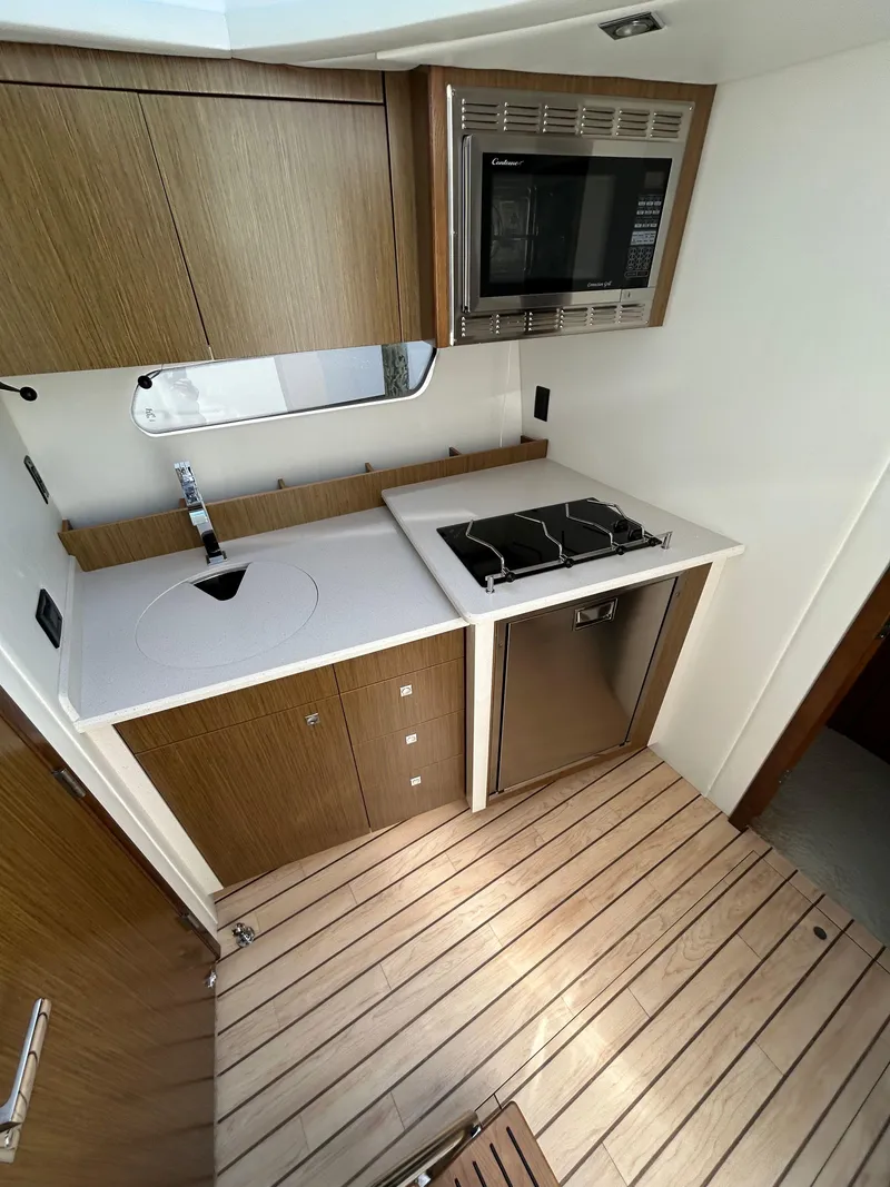 Slide: The Image of 2014 Cruisers Yachts 41 Cantius kitchen with stove, microwave, and wooden cabinetry. - 15
