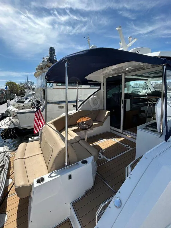 Slide: The Image of 2014 Cruisers Yachts 41 Cantius with outdoor seating, canopy, and American flag, docked under blue sky. - 4