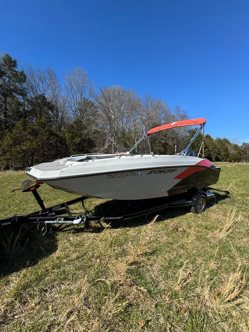 The Image of 2022 Starcraft SVX 171 OB boat on trailer in grassy field, clear sky background. - 0