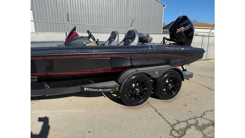 Slide: The Image of 2025 Triton 20XP Patriot boat on trailer, black and red design, parked outdoors. - 4