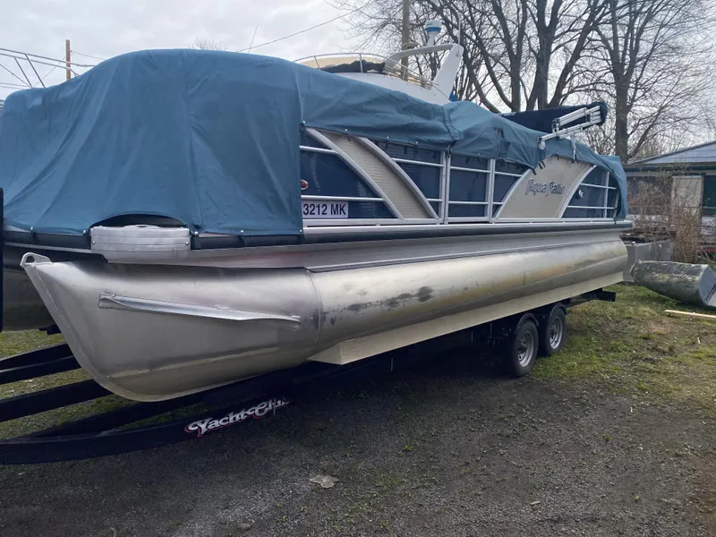 Slide: The Image of 2014 Godfrey 22 PF pontoon boat covered with a blue tarp on a trailer. - 0