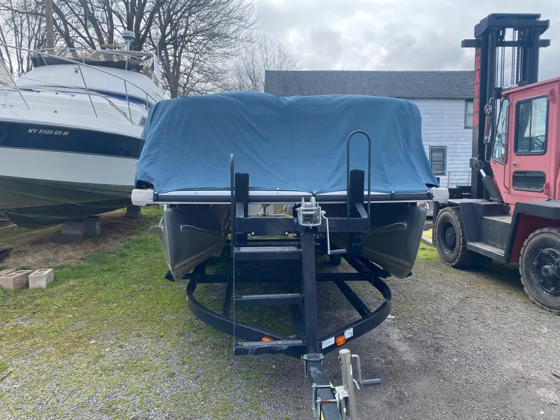 Slide: The Image of Covered 2014 Godfrey 22 PF boat on trailer, parked outdoors near other vehicles. - 1