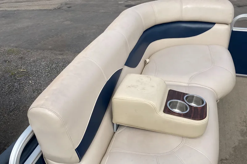 Slide: The Image of 2014 Godfrey 22 PF boat seating with beige and navy upholstery, featuring built-in cup holders. - 10