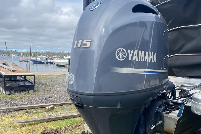 Slide: The Image of Yamaha 115 outboard motor on a 2014 Godfrey 22 PF boat near a marina. - 2