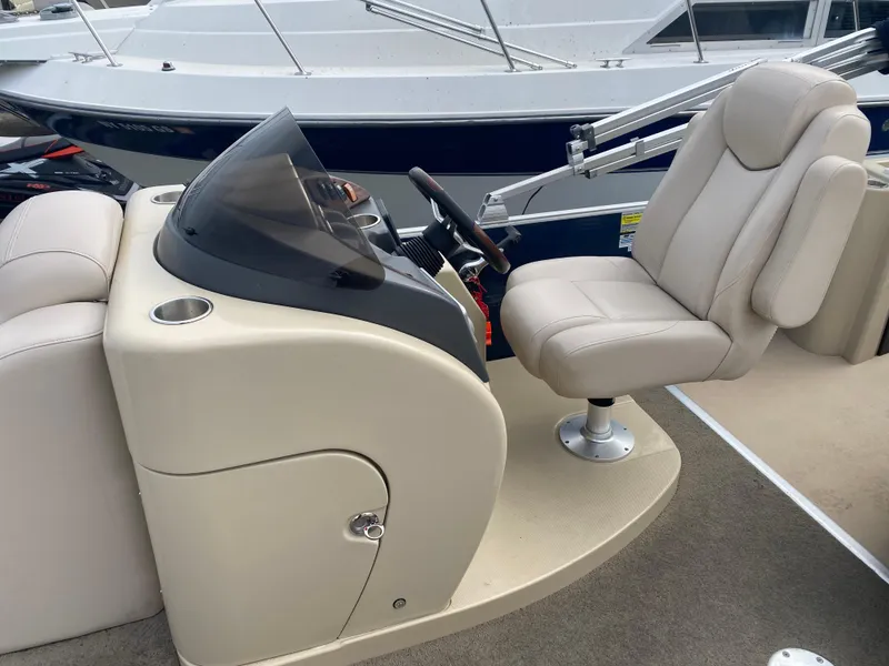 Slide: The Image of Captain's seat and console of a 2014 Godfrey 22 PF boat, featuring beige upholstery. - 8