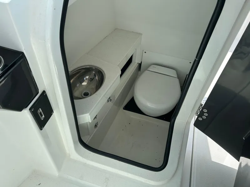 Slide: The Image of 2023 Blackfin 272 DC boat interior with compact bathroom, featuring a toilet and sink. - 10