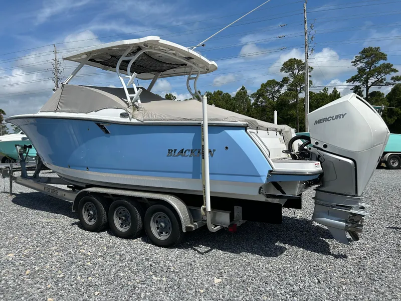 Slide: The Image of 2023 Blackfin 272 DC boat on trailer with Mercury engine, parked on gravel. - 4