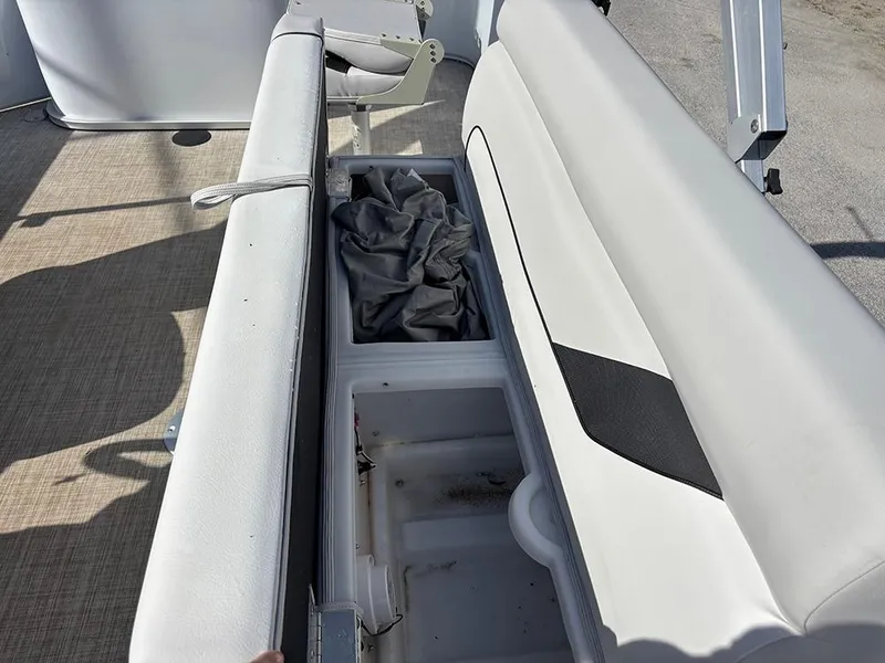 Slide: The Image of 2023 SunCatcher Select 18F boat seat storage compartment with open lid and fabric inside. - 12