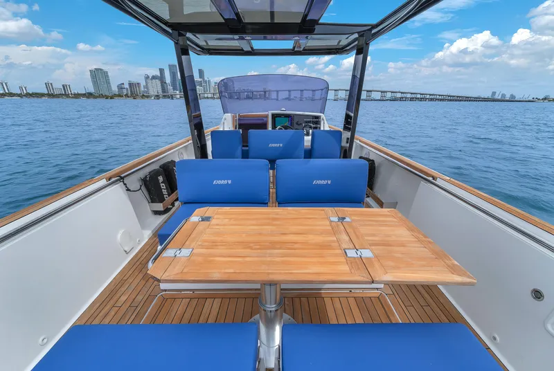 Slide: The Image of 2019 Fjord 38 boat with blue seating and wooden table on open water. - 22