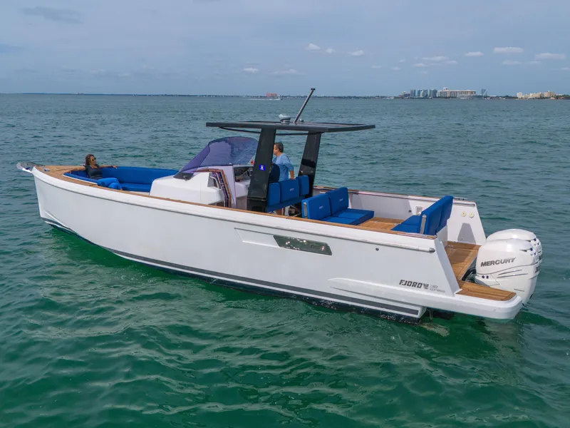 Slide: The Image of 2019 Fjord 38 boat cruising on open water with blue seating and Mercury engine. - 31