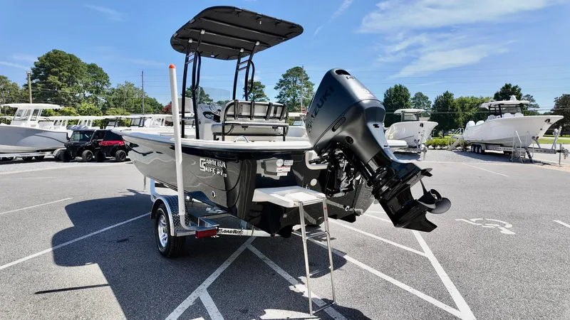 Slide: The Image of 2025 Carolina Skiff 21 LS Stealth Edition boat with outboard motor in a parking lot. - 3