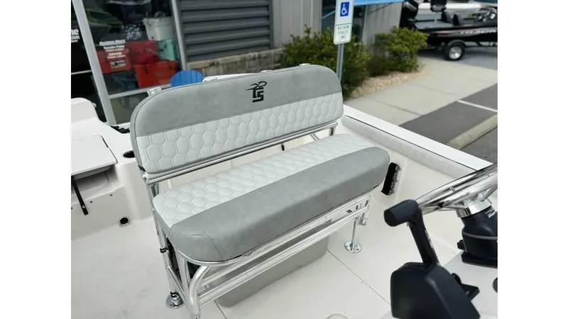 Slide: The Image of 2025 Carolina Skiff 21 LS boat seat with gray upholstery and logo, parked outdoors. - 10