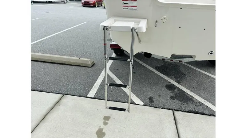 Slide: The Image of 2025 Carolina Skiff 21 LS boat with a foldable rear ladder in a parking lot. - 16