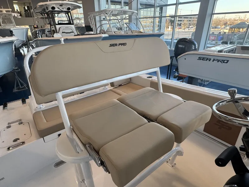 Slide: The Image of 2025 Sea Pro 225 FLX boat interior with beige seating and steering wheel. - 8