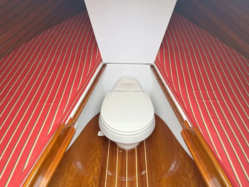 Slide: The Image of 2007 Hinckley Talaria 29 R boat interior with striped cushions and a marine toilet. - 38