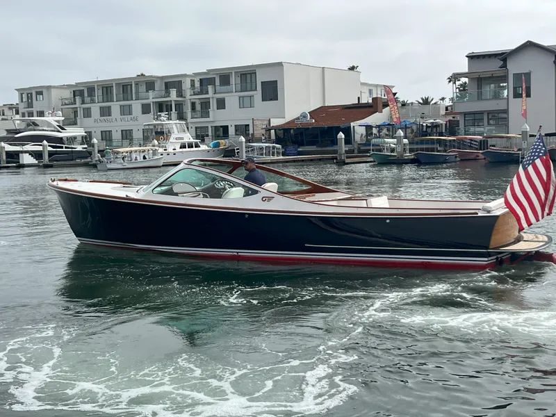 Slide: The Image of 2007 Hinckley Talaria 29 R boat cruising in a marina with buildings in the background. - 5