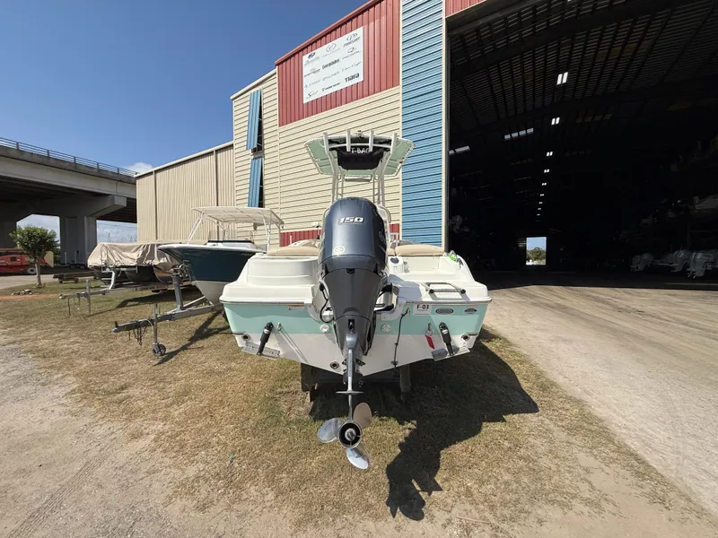 Slide: The Image of 2016 NauticStar 2102 Legacy boat with outboard motor, parked outside a large storage facility. - 11