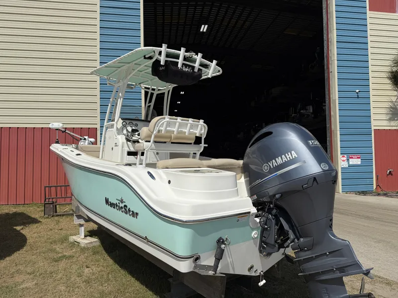 Slide: The Image of 2016 NauticStar 2102 Legacy boat with Yamaha engine, parked outside a large garage. - 14
