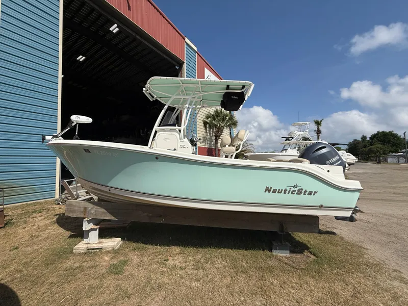 Slide: The Image of 2016 NauticStar 2102 Legacy boat on display outside a blue and red building. - 15