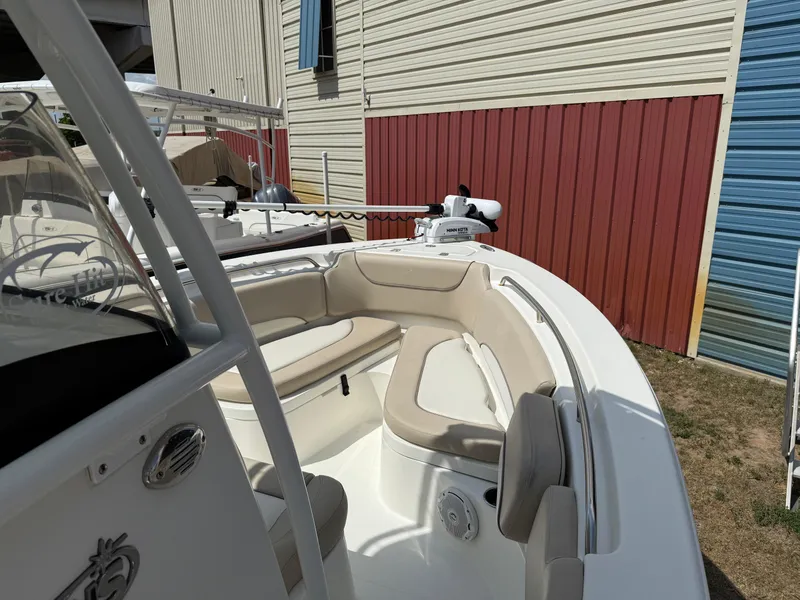 Slide: The Image of 2016 NauticStar 2102 Legacy boat with beige seating, docked near a red and blue building. - 9