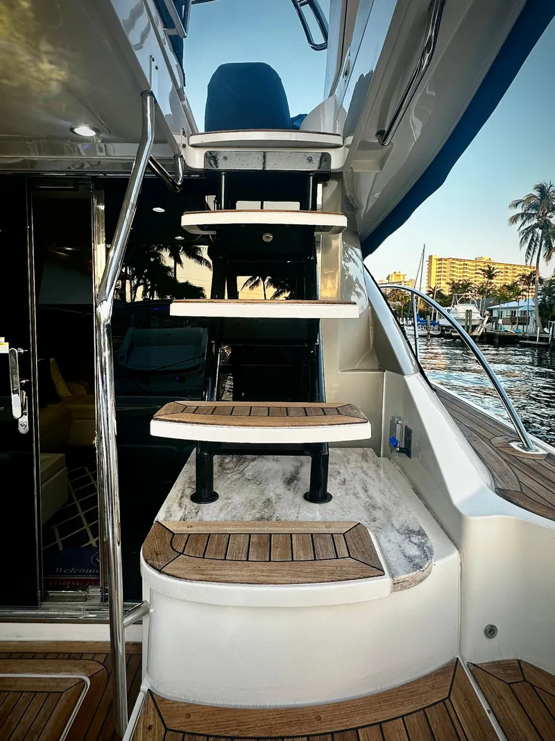 Slide: The Image of 2015 Sea Ray 510 Fly yacht with elegant wooden steps and marina view. - 12