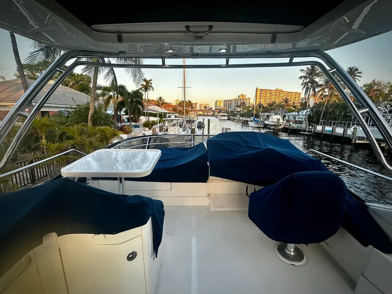Slide: The Image of 2015 Sea Ray 510 Fly yacht deck with marina view, covered seating, and table. - 13