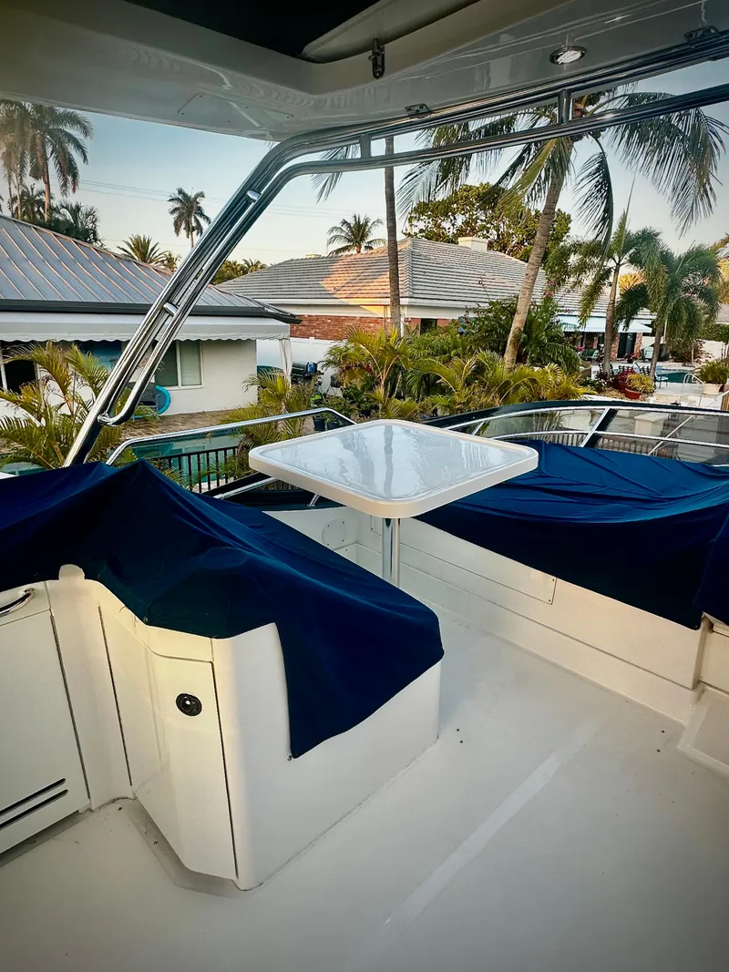 Slide: The Image of 2015 Sea Ray 510 Fly yacht deck with seating, table, and tropical backdrop. - 14