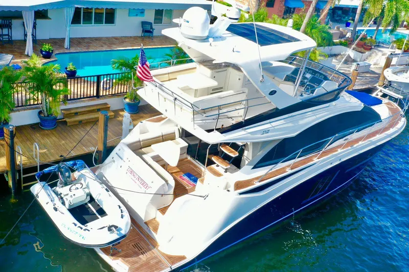 Slide: The Image of 2015 Sea Ray 510 Fly yacht docked by a poolside, featuring sleek design and luxury amenities. - 6