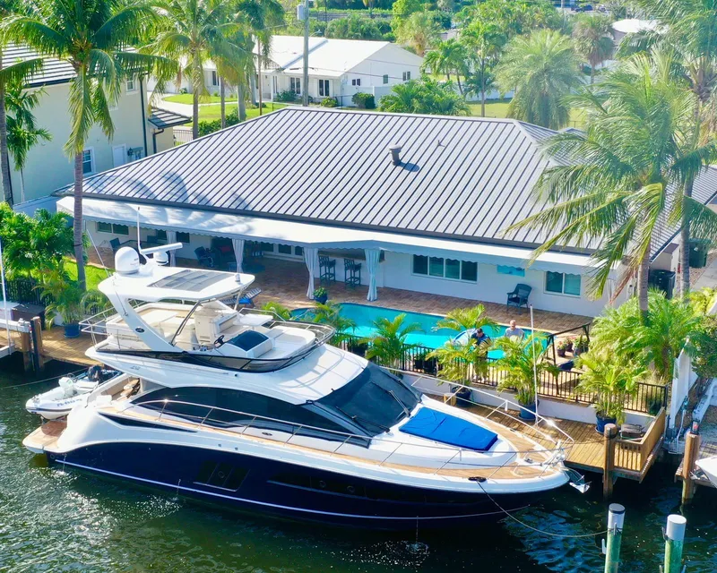 Slide: The Image of 2015 Sea Ray 510 Fly yacht docked by a waterfront home with a pool and palm trees. - 9