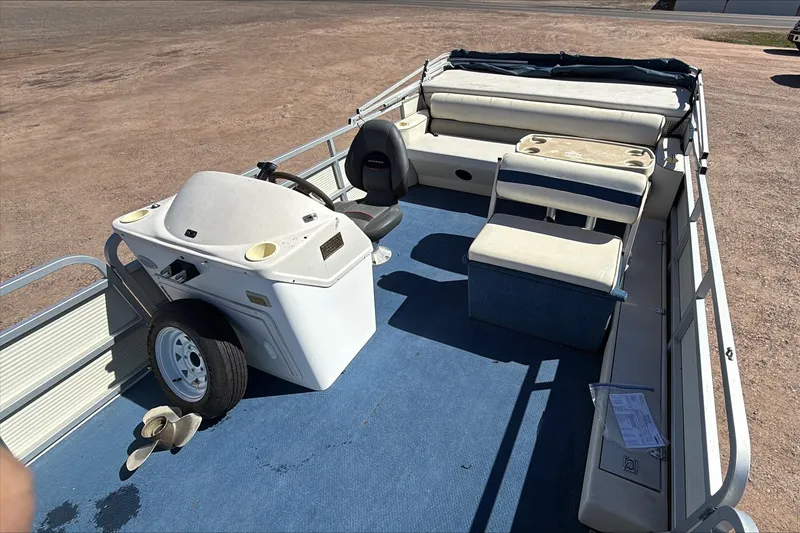 Slide: The Image of 1999 Smoker Craft Party Pontoon with blue carpet and white seating on a sunny day. - 5