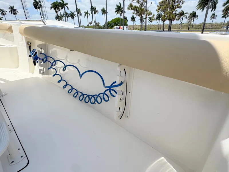 Slide: The Image of 2017 Key West 244 Center Console boat interior with blue coiled hose and palm trees in background. - 29