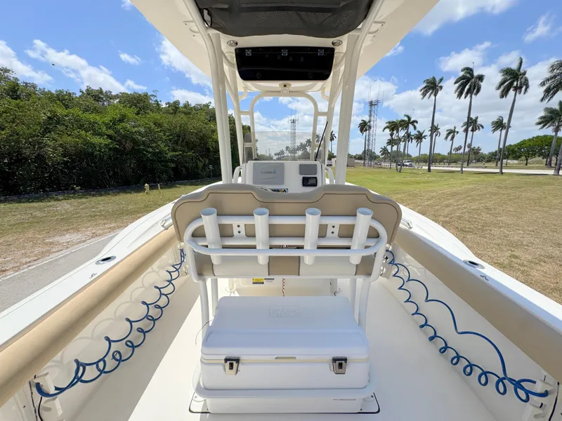 Slide: The Image of 2017 Key West 244 Center Console boat interior with rod holders and cooler, set against a tropical backdrop. - 31