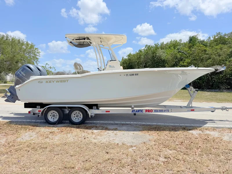 Slide: The Image of 2017 Key West 244 Center Console boat on trailer, parked outdoors under a blue sky. - 5