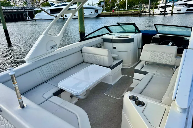 Slide: The Image of 2021 Sea Ray SDX 270 boat interior with spacious seating and table, docked by the water. - 10