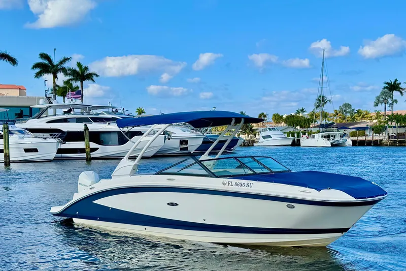 Slide: The Image of 2021 Sea Ray SDX 270 boat on water, surrounded by yachts and palm trees. - 2