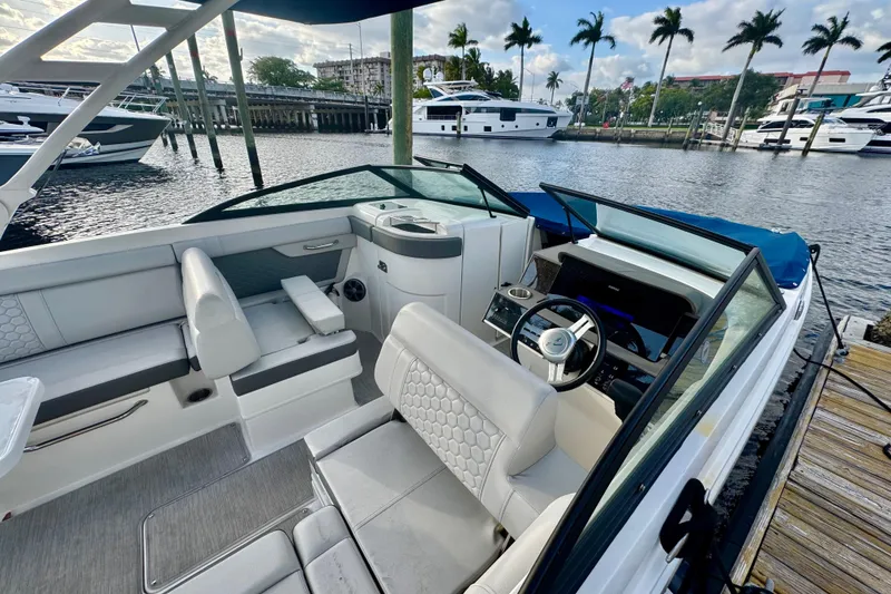 Slide: The Image of 2021 Sea Ray SDX 270 boat interior at marina, featuring sleek seating and modern dashboard. - 29
