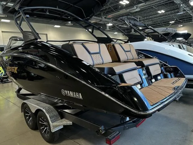 Slide: The Image of 2025 Yamaha Boats 255XD in showroom, sleek black design on trailer. - 25