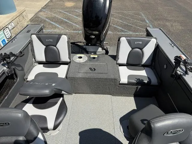 Slide: The Image of 2012 Lund 1750 Tyee boat interior with seating and motor, parked on pavement. - 12
